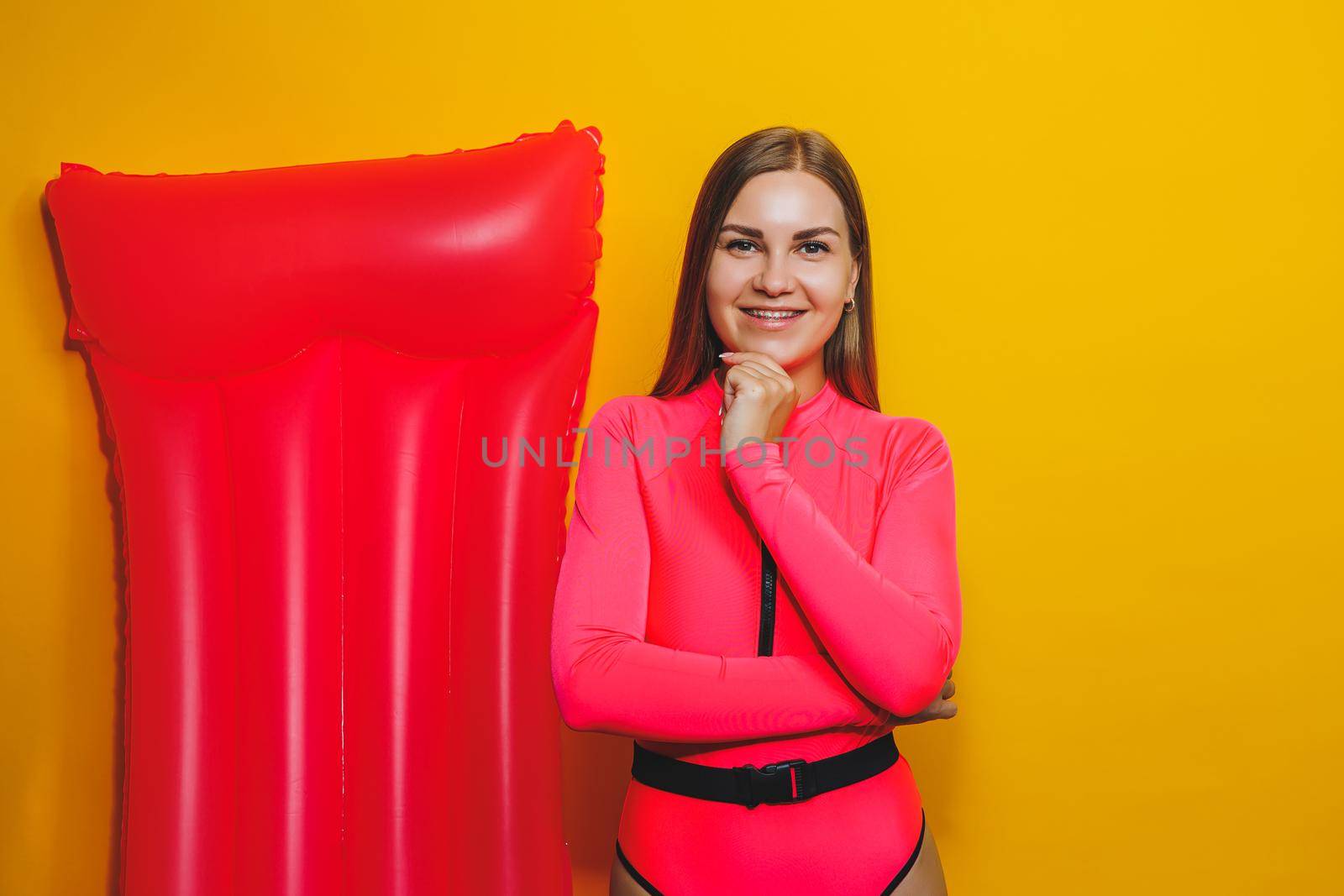 Young woman slim body pink one piece swimsuit on pink air mattress isolated on bright yellow color studio background summer hotel swimming pool sea vacation sun tanning concept. Place for text