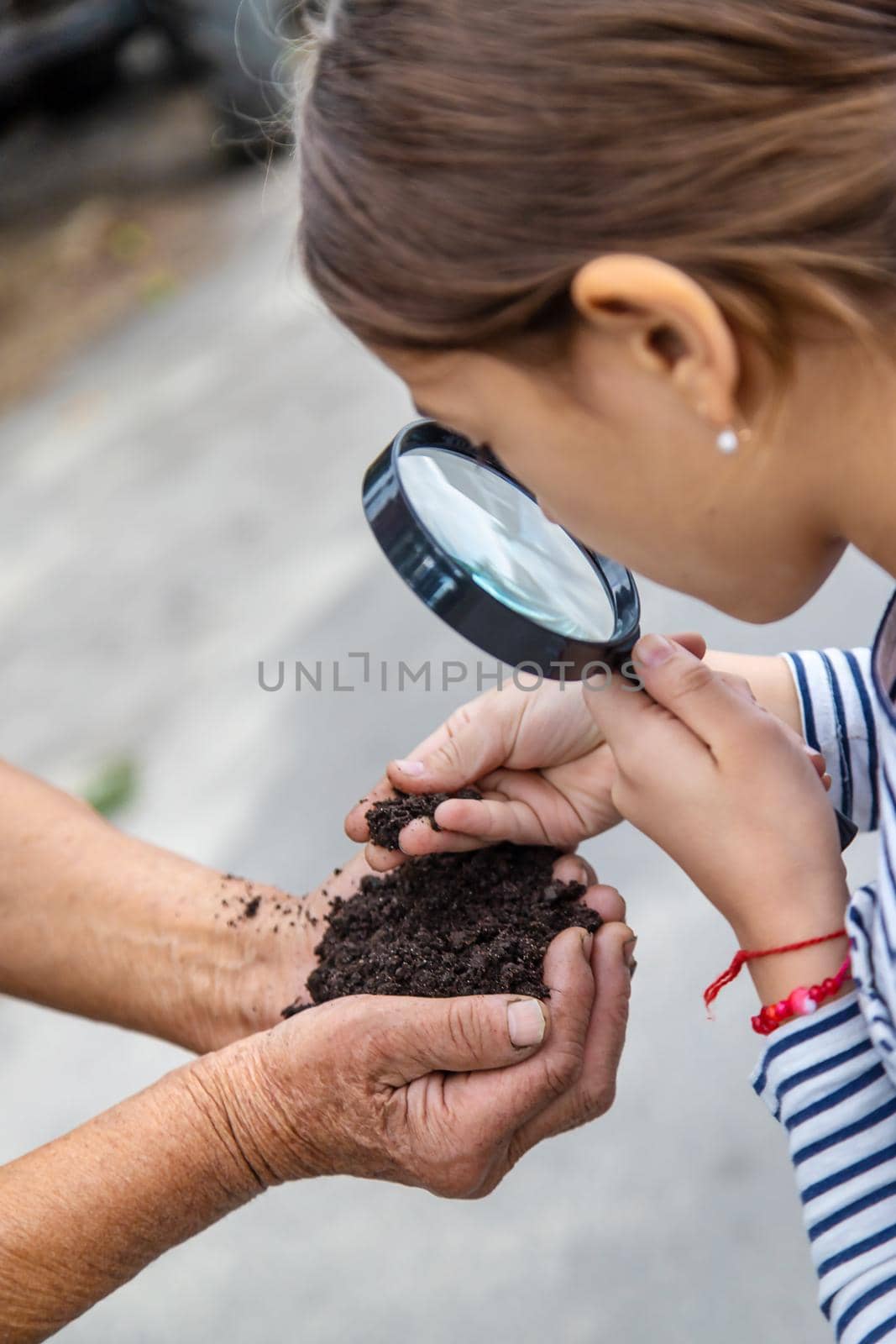 The child examines the soil with a magnifying glass. Selective focus. by yanadjana