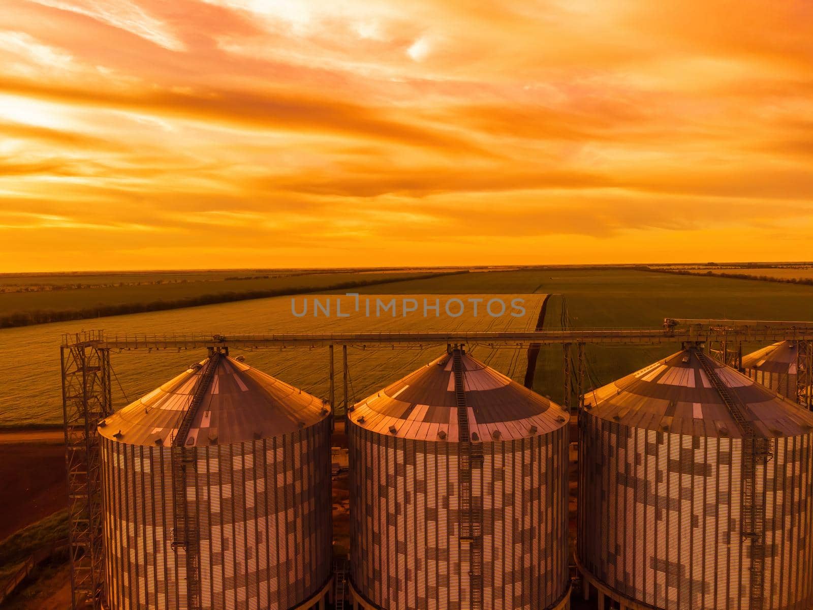 Grain elevator. Metal grain elevator in agricultural zone. Agriculture storage for harvest. Grain silos on green nature background. Exterior of agricultural factory