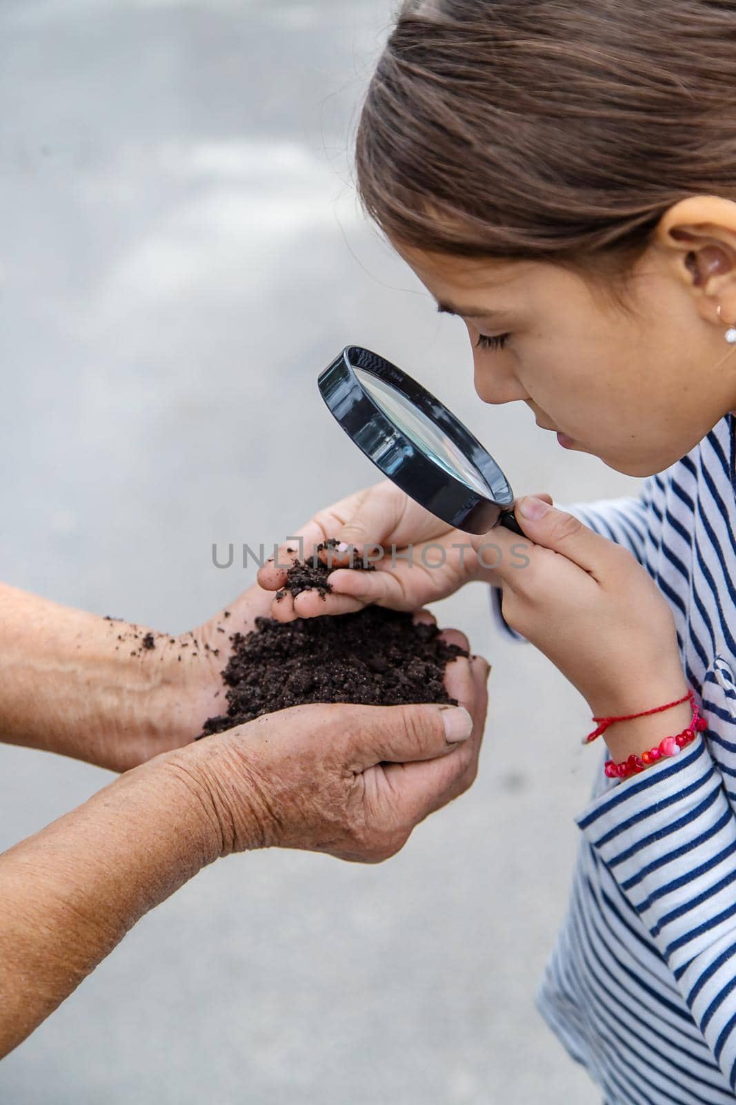 The child examines the soil with a magnifying glass. Selective focus. Kid.