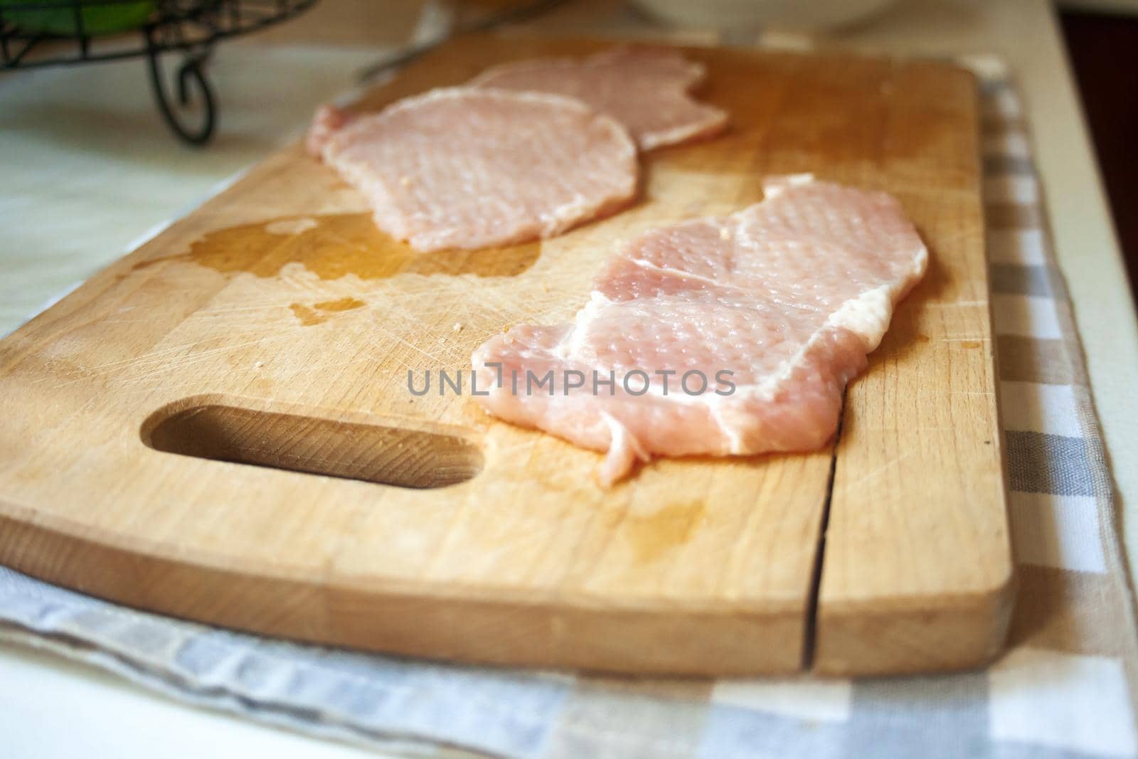 Raw pork loin cutlets on a board, kitchen view