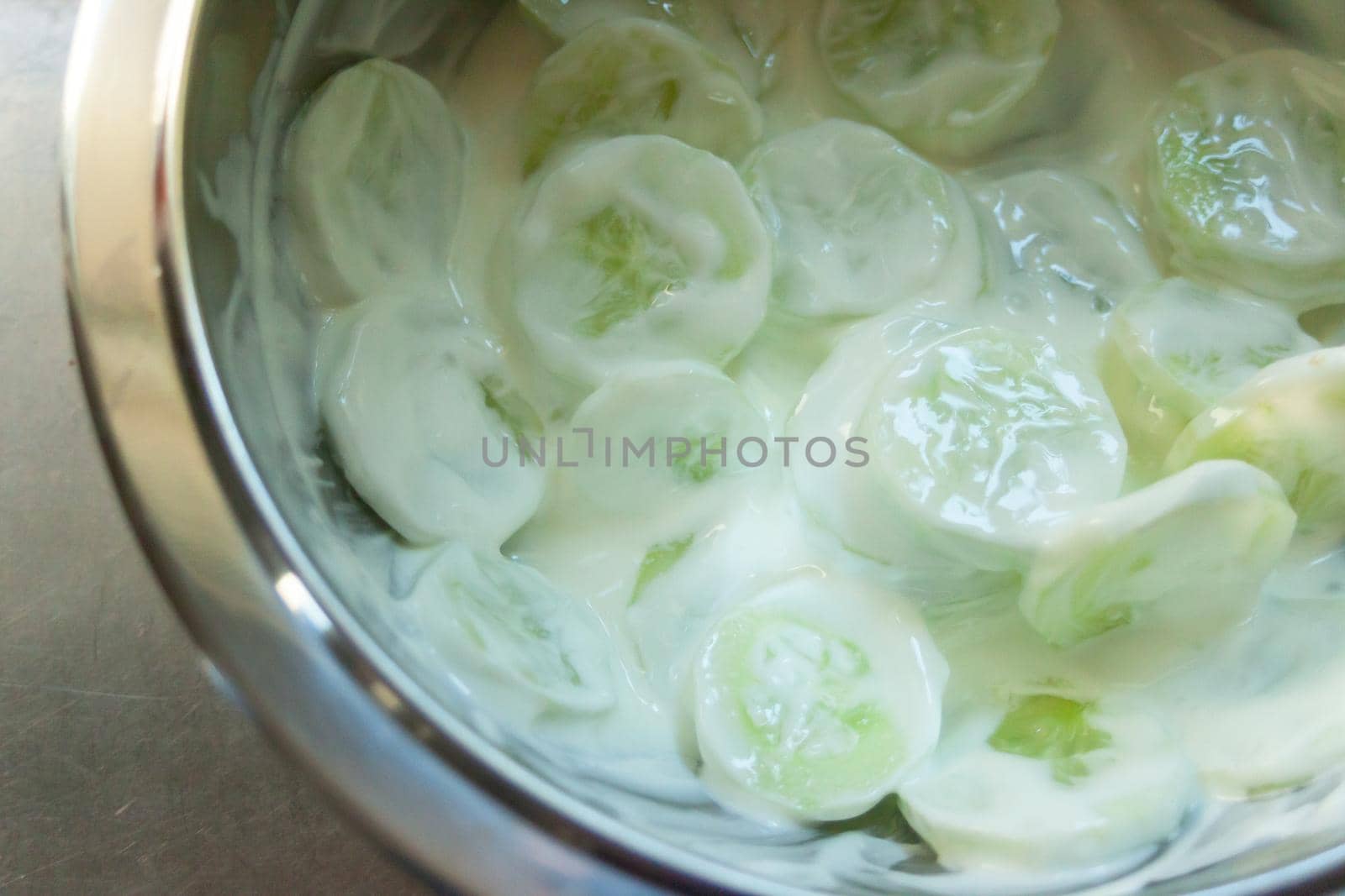 Cucumber salad with cream in a bowl, top view and close up
