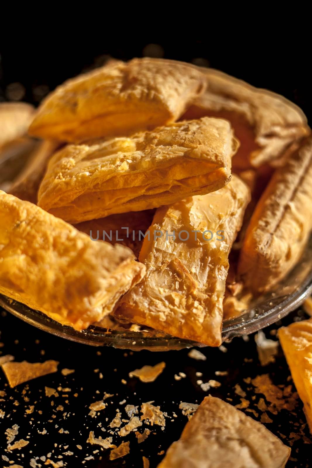 Classic jeera Khari or puff pastry in a glass plate on a black surface. Shot of freshly baked puff pastry snack on a serving plate.