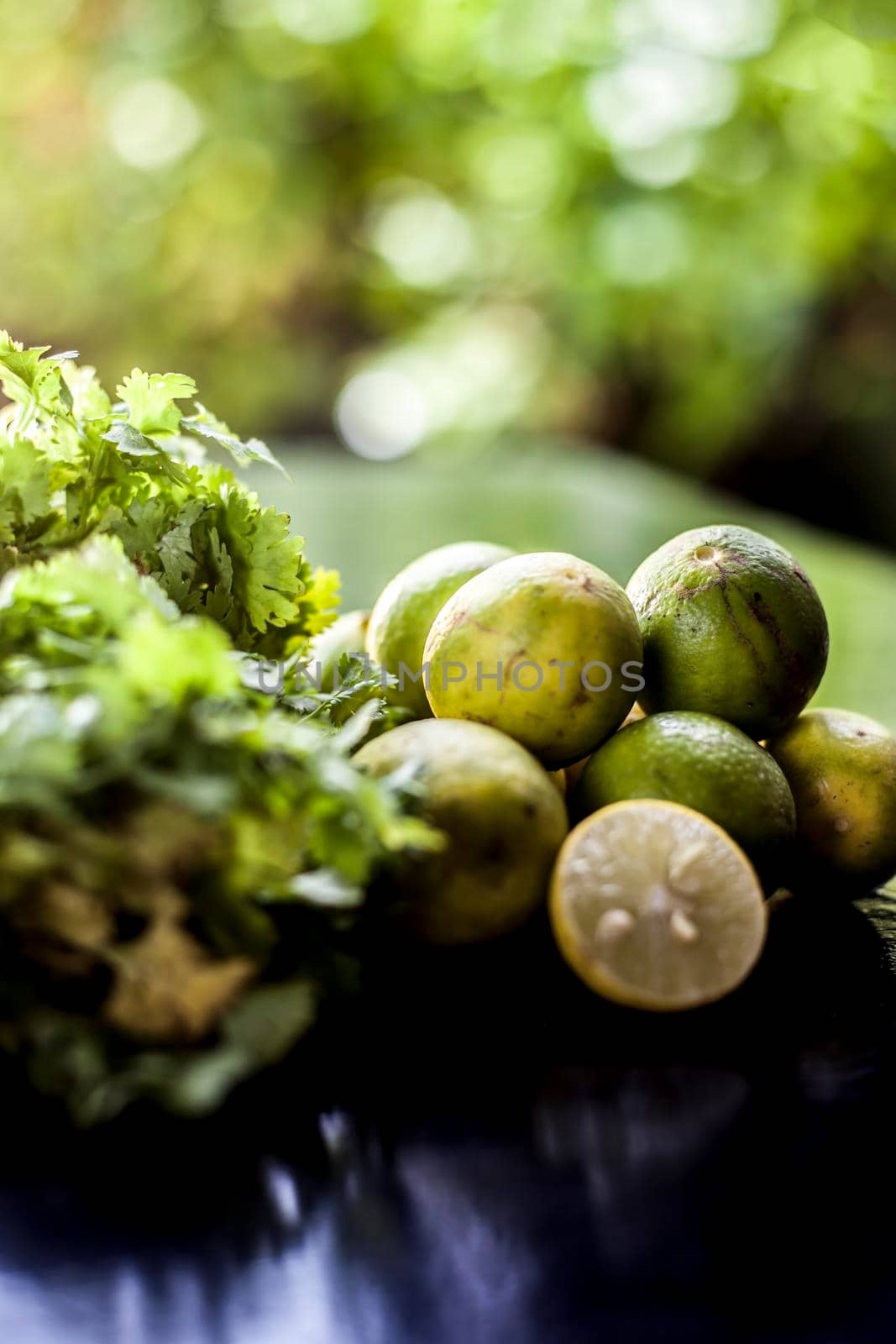 Face mask for blackhead and dry skin on a surface consisting of some coriander leaves and fresh lemon juice. Shot of fresh parsley leaves and lemons for blackhead removal face mask.