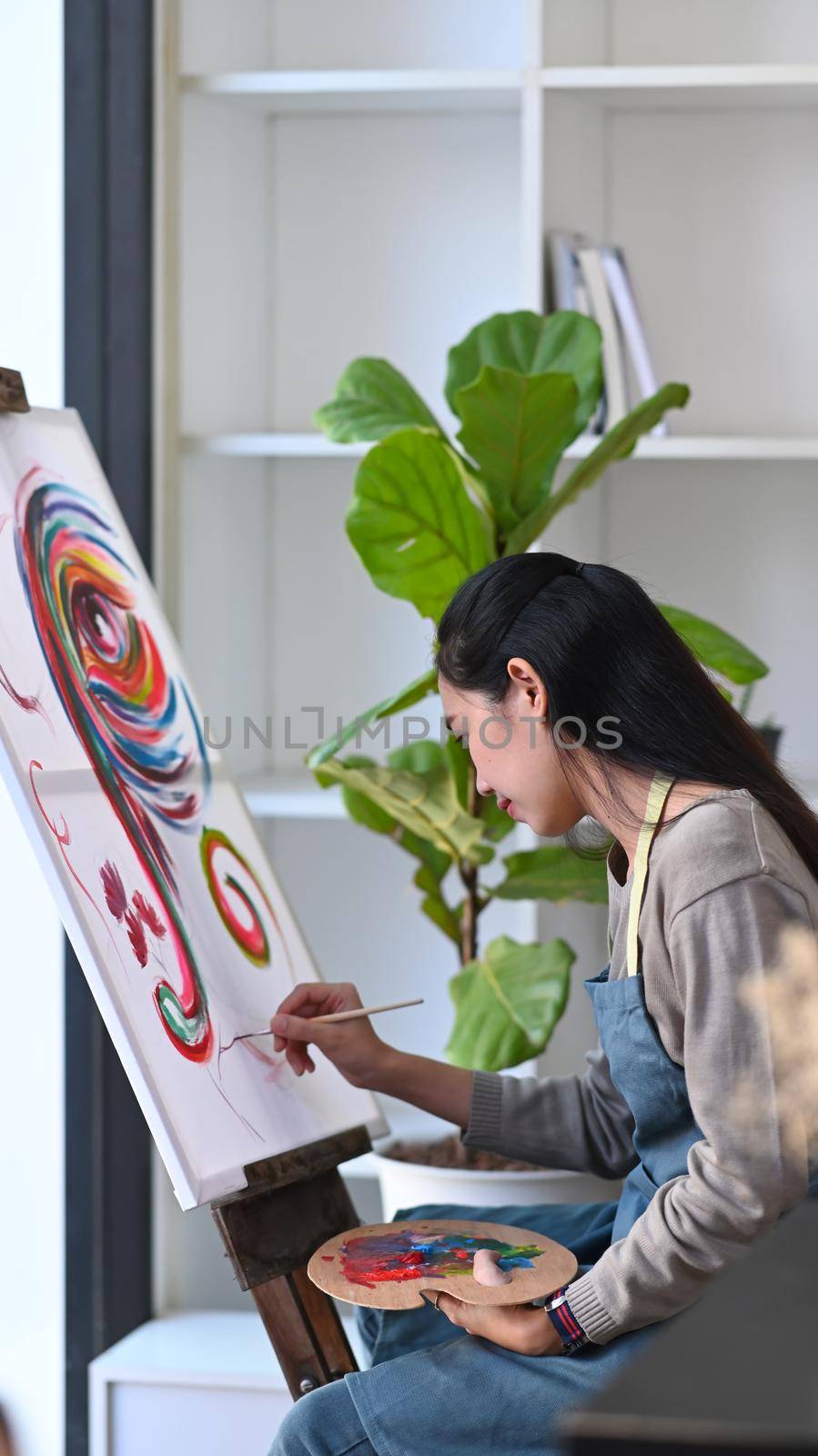 Young asian woman painter painting on canvas in art studio. by prathanchorruangsak