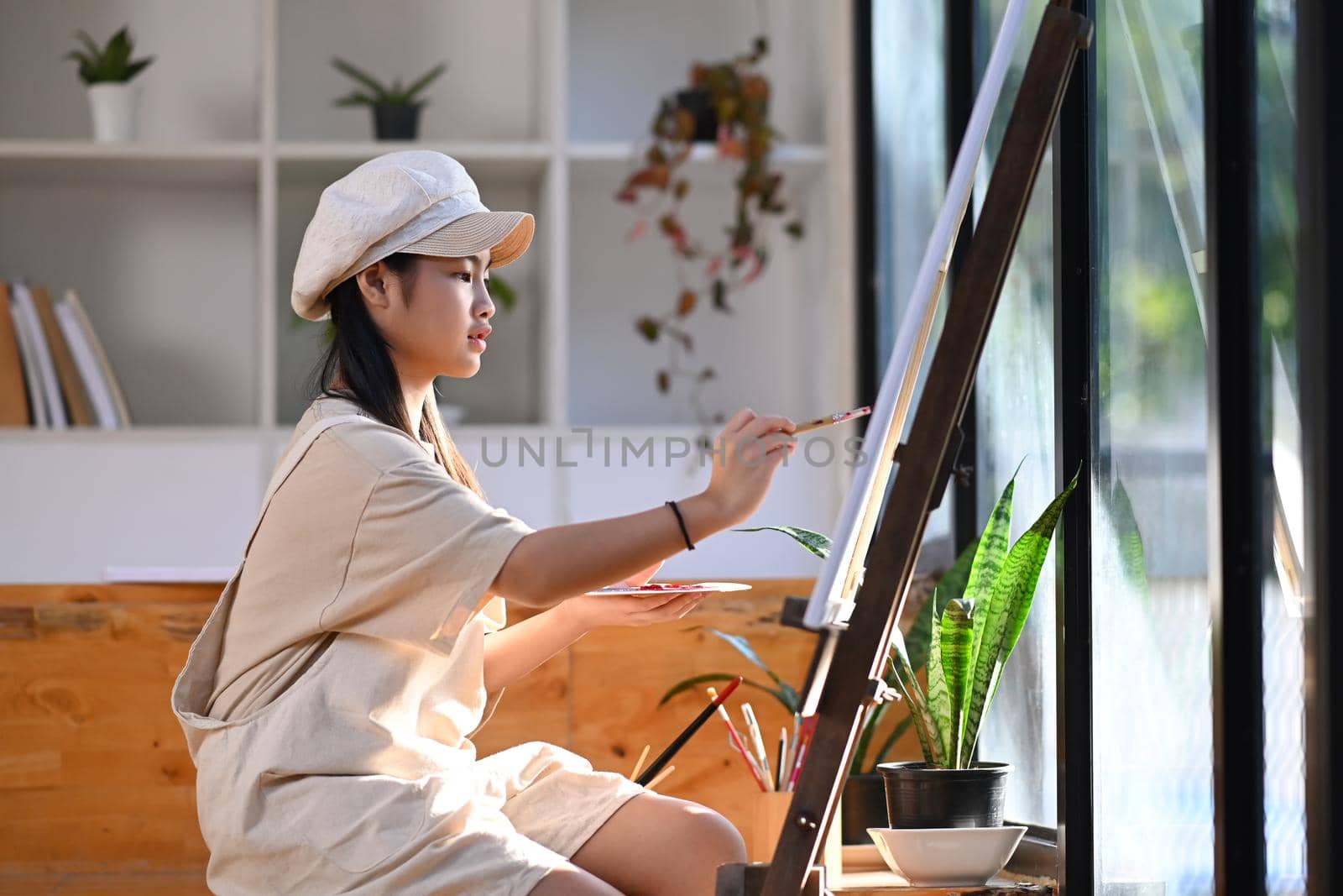 Asian girl painting picture with water color in art class.