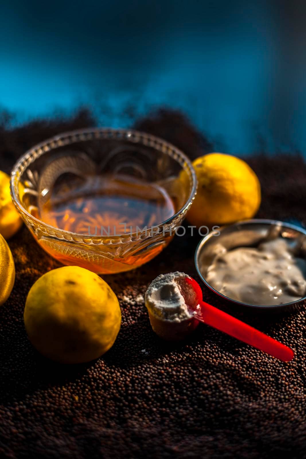 Mustard seed face mask for glowing skin on black surface with raw fresh lemons, mustard seeds, yogurt, honey, and cornflour. by mirzamlk