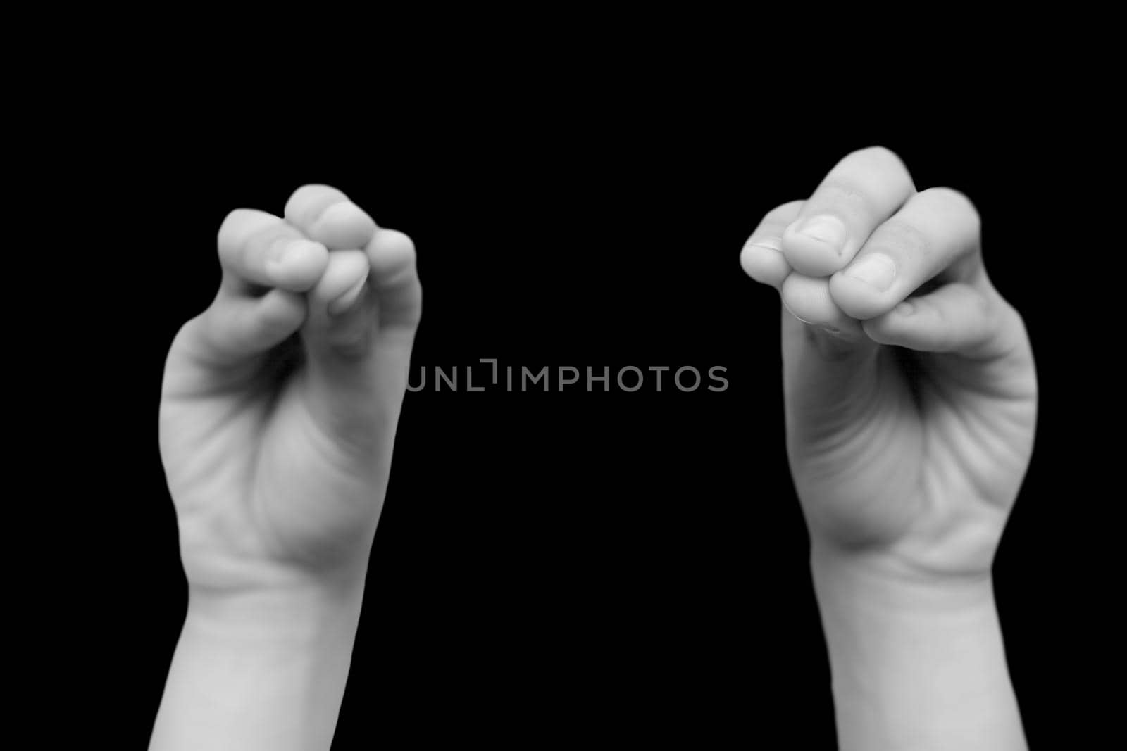 pair of male hands doing Mukula Mudra isolated on a black background.