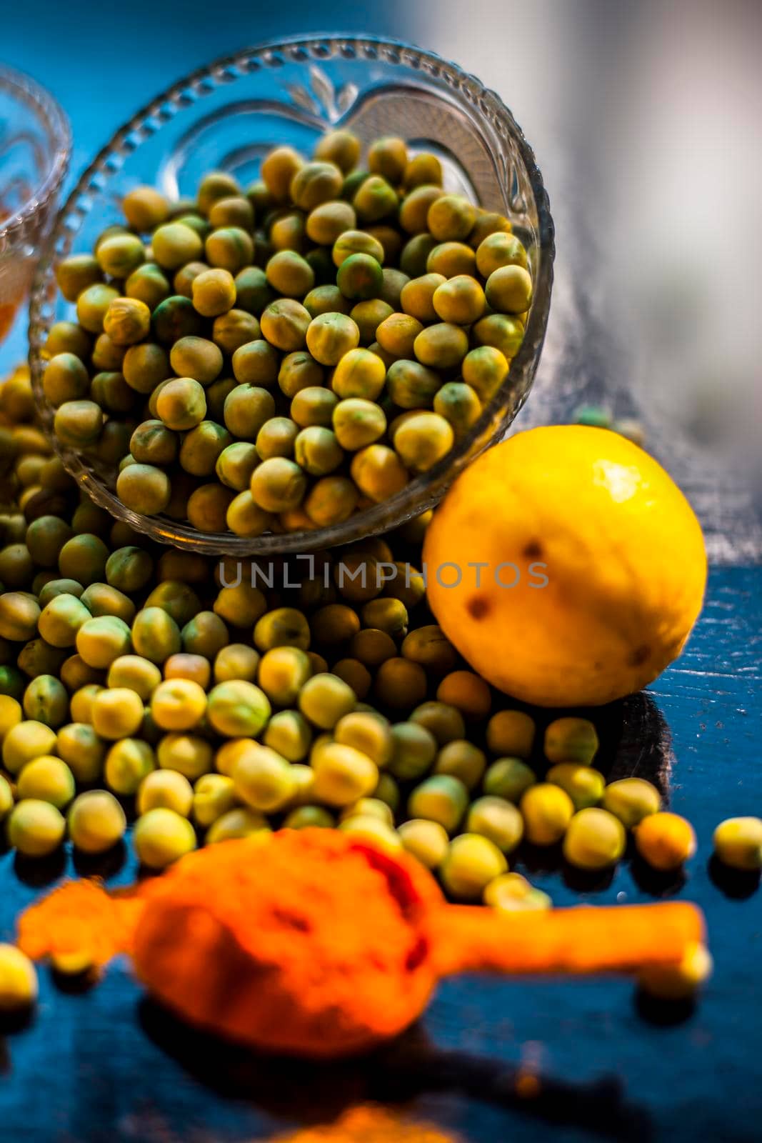 Green pea face mask for glowing and radiant skin consisting of some green peas, honey, yogurt, turmeric, lemons, and aloe vera gel on black background.