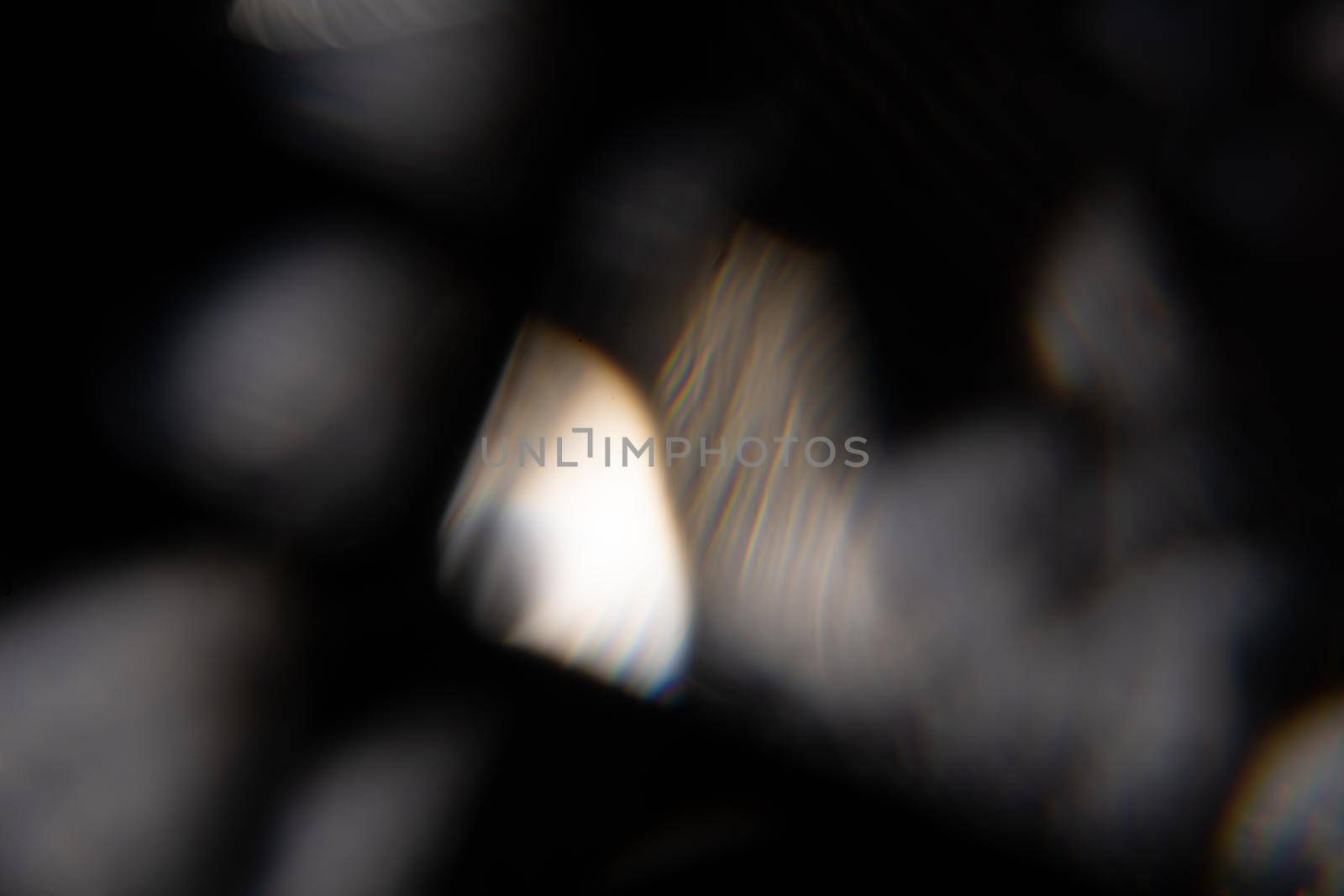 Blue light flare prism rainbow flares overlay effect on black background, light crossing crystals, prismatic sun catcher reflections rays. Abstract blurred colourful lens flare bokeh on dark backdrop