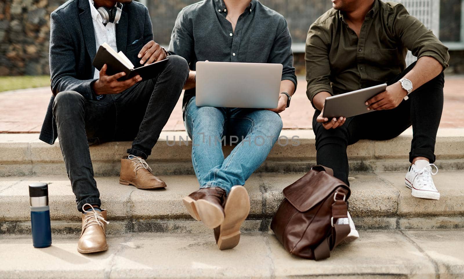 Casual guys, young men or students, outdoors on business, education or college campus talking and discussing ideas during break. Creative team has an informal meeting for inspiration and innovation by YuriArcurs