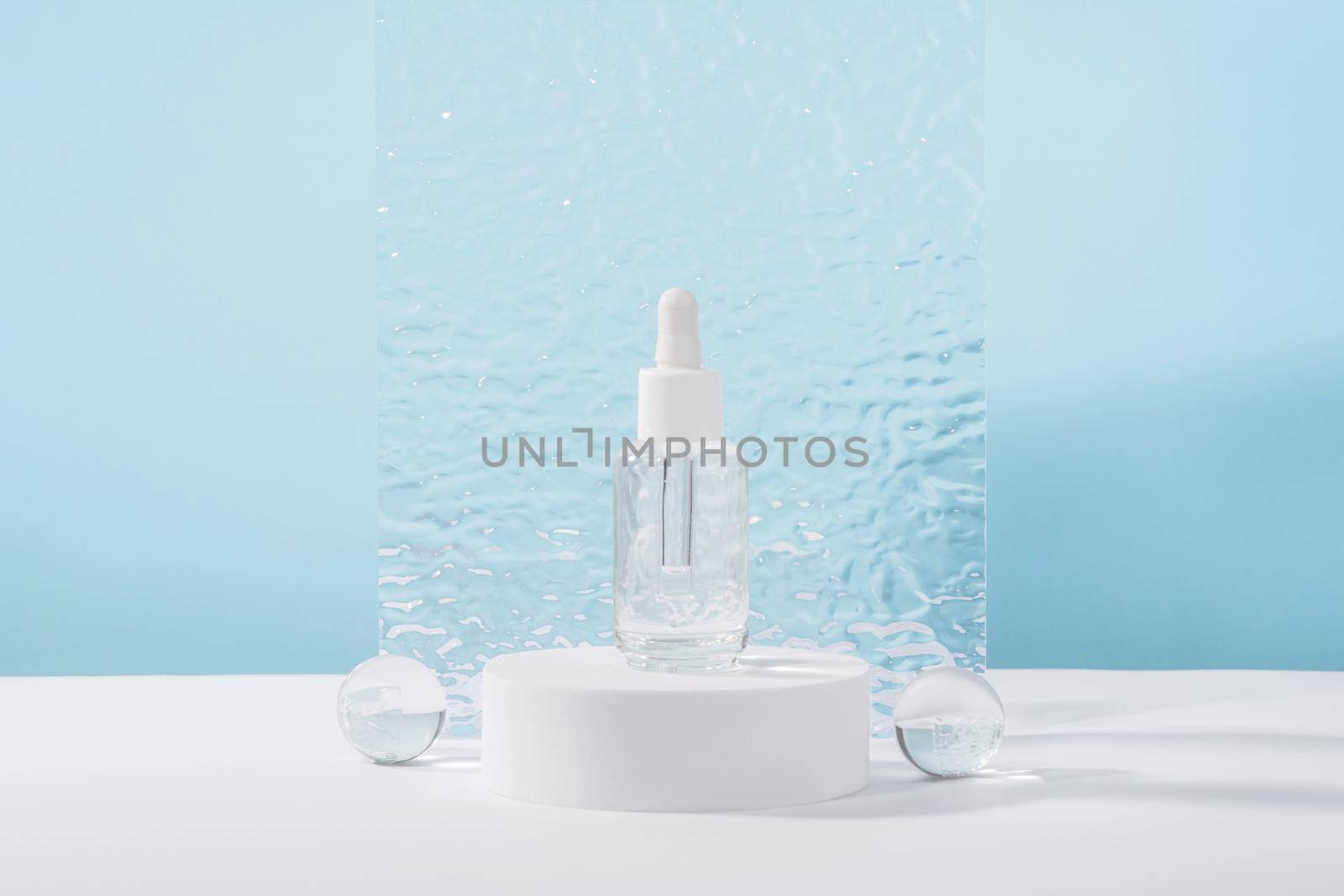 Serum cosmetic bottle with peptides and retinol on pedestal with ribbed plate on blue background. Hyaluronic acid cosmetics product mock up packaging with stylish props. Serum beauty dropper by photolime