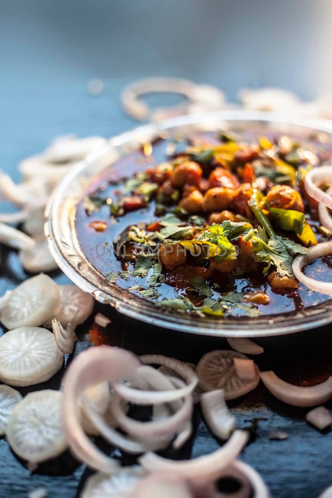 Full breakfast plate on the black surface. Indian Delhi style Chole bhature along with some onion rings and pudhina/mint chutney on a black surface.