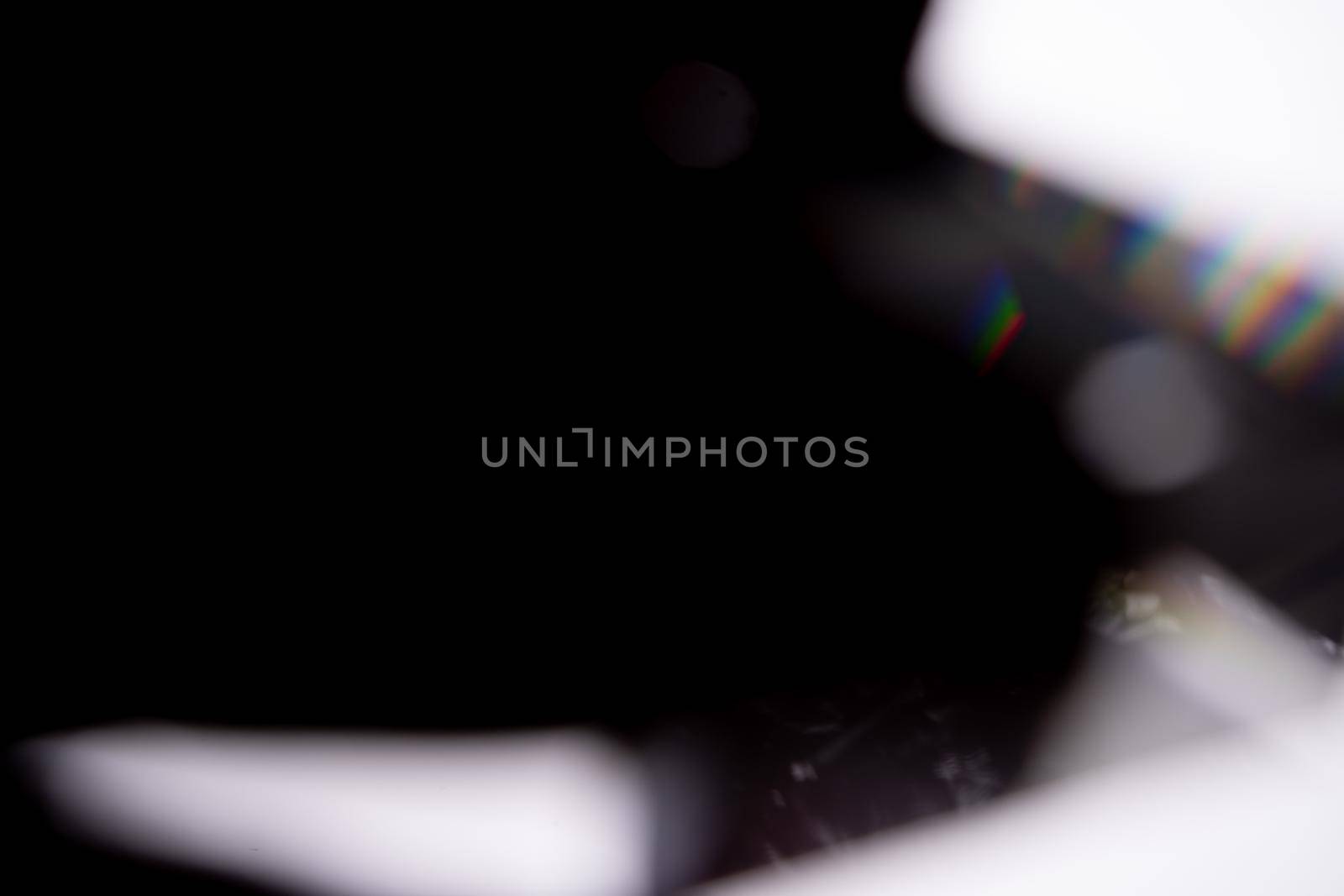 Blue light flare prism rainbow flares overlay effect on black background, light crossing crystals, prismatic sun catcher reflections rays. Abstract blurred colourful lens flare bokeh on dark by photolime