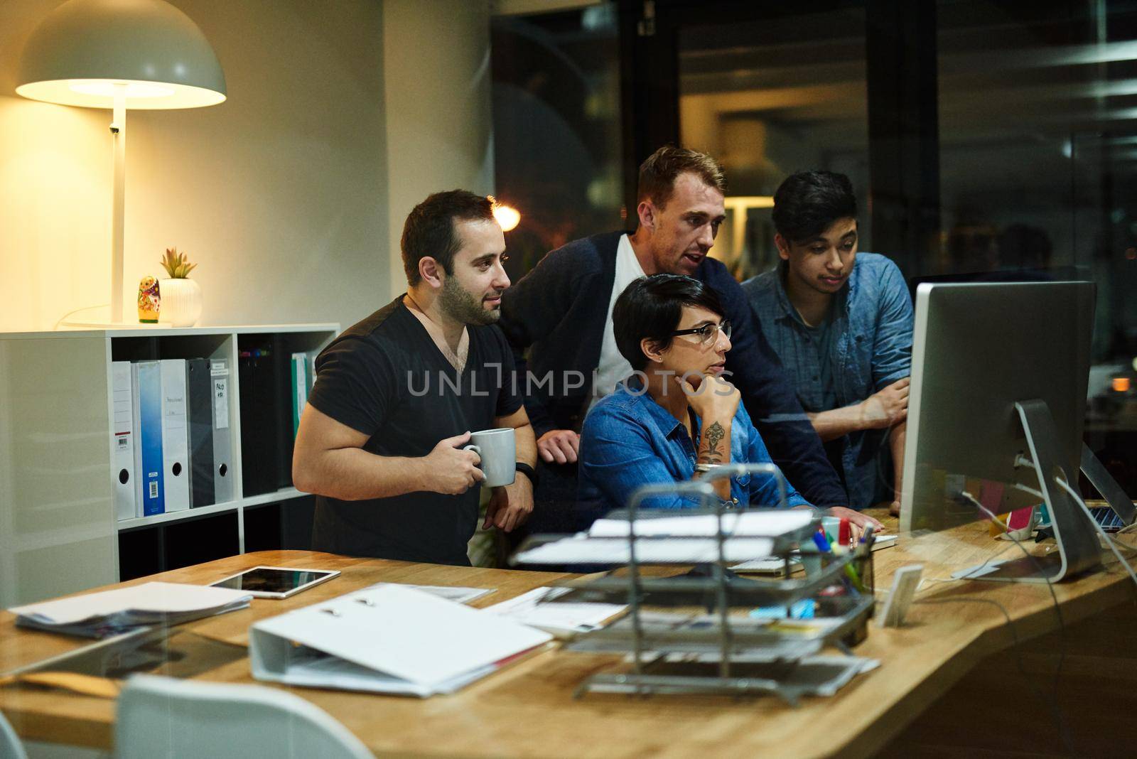 Teamwork at its best. employees working in an office at night. by YuriArcurs