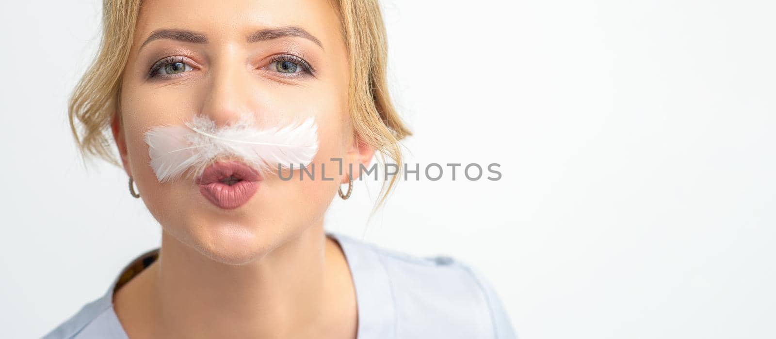 Funny beautician with a white feather-like mustache poses on white background, depilation concept