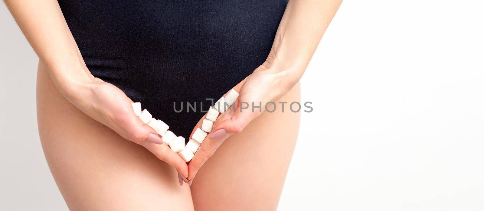 Woman holding sugar cubes on bikini zone, the concept of intimate depilation, problems of intimate hygiene