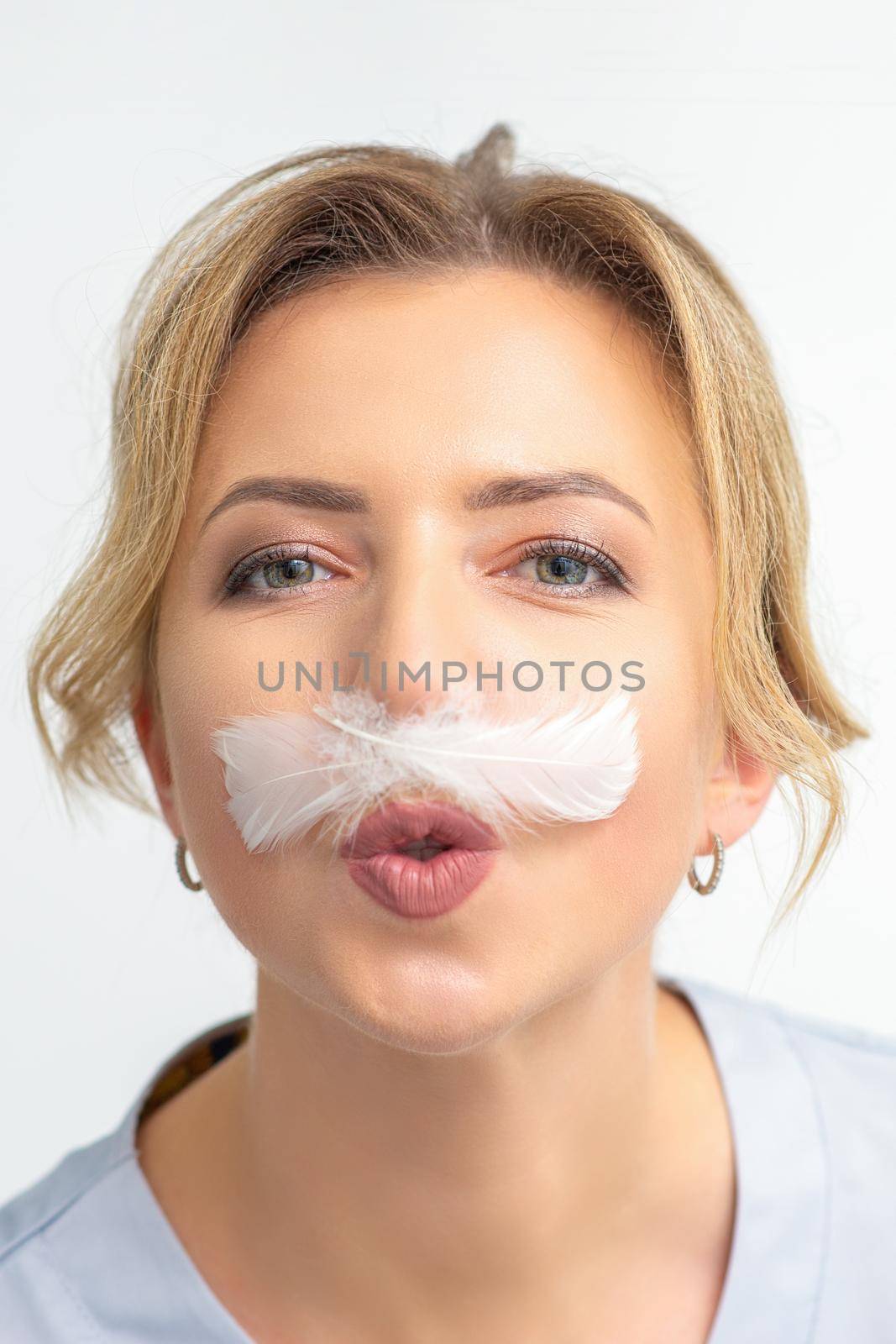 Funny beautician with a white feather-like mustache poses on white background, depilation concept