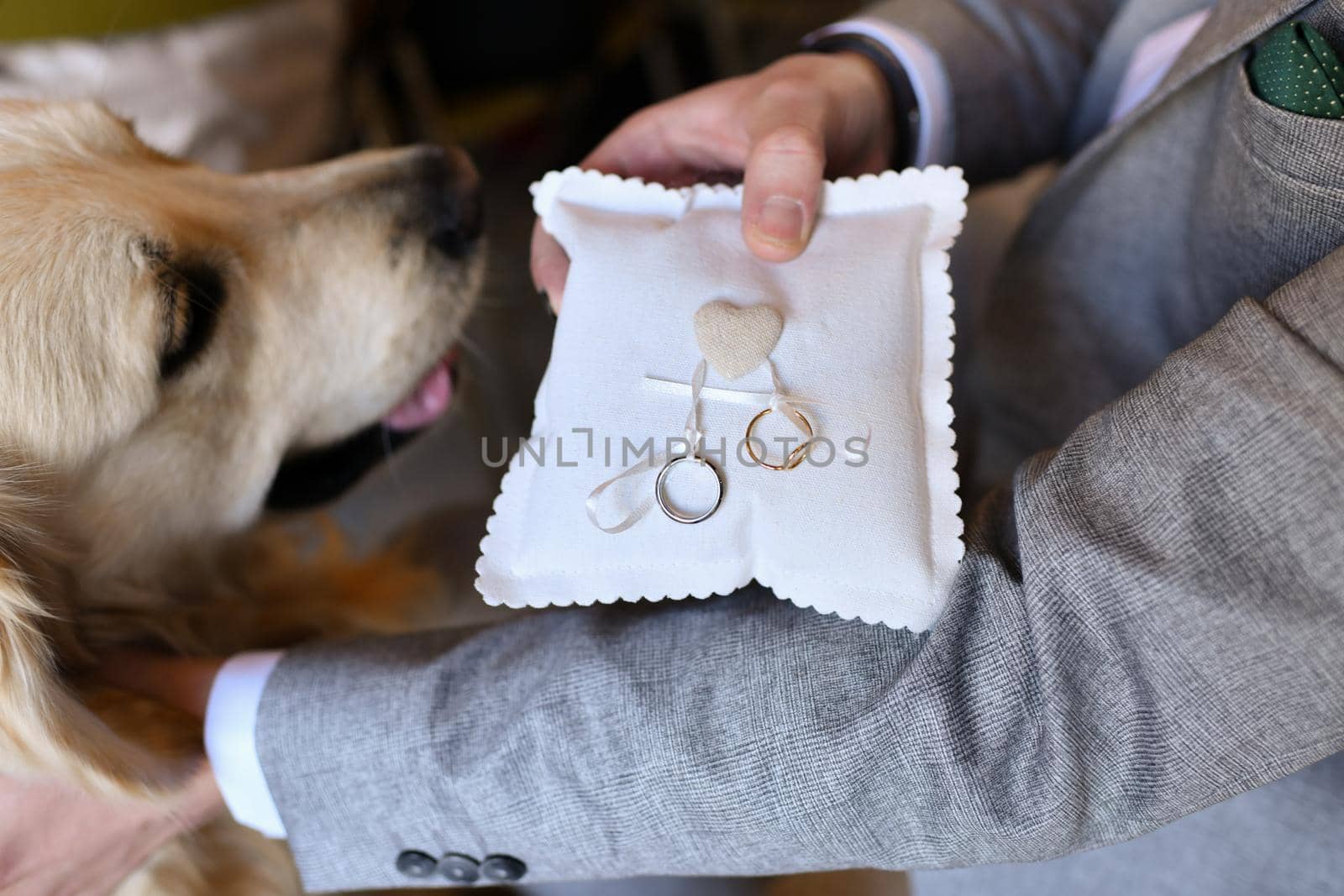 A groom takes the wedding rings on the pillow