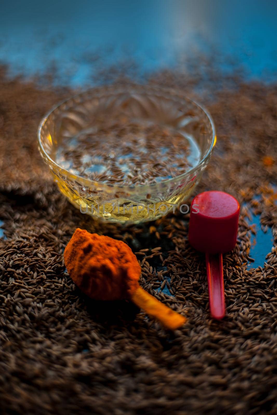 DIY Face mask for smooth and glowing skin. Shot of cumin seeds along with some turmeric on a brown surface making a glowing skin face mask all together. by mirzamlk