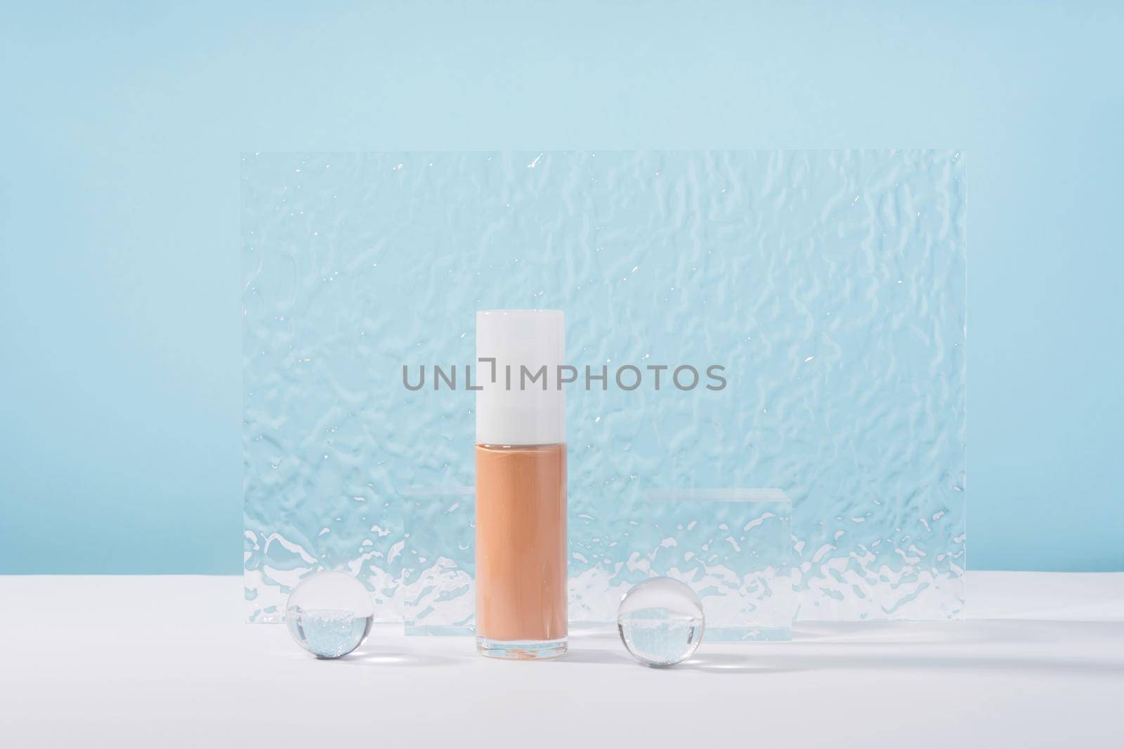 Cosmetic liquid foundation nude cream bottle mockup on blue backdrop. Beige concealer base cosmetics product mock up with stylish props. Skincare beauty primer