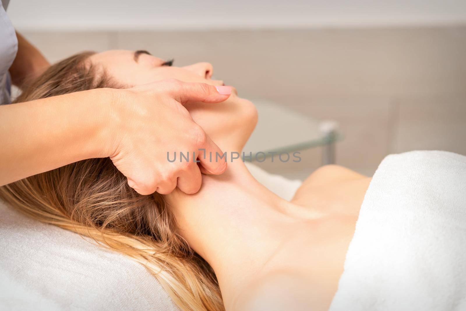 Beautician making lymphatic drainage face massage or facelifting massage at the beauty salon