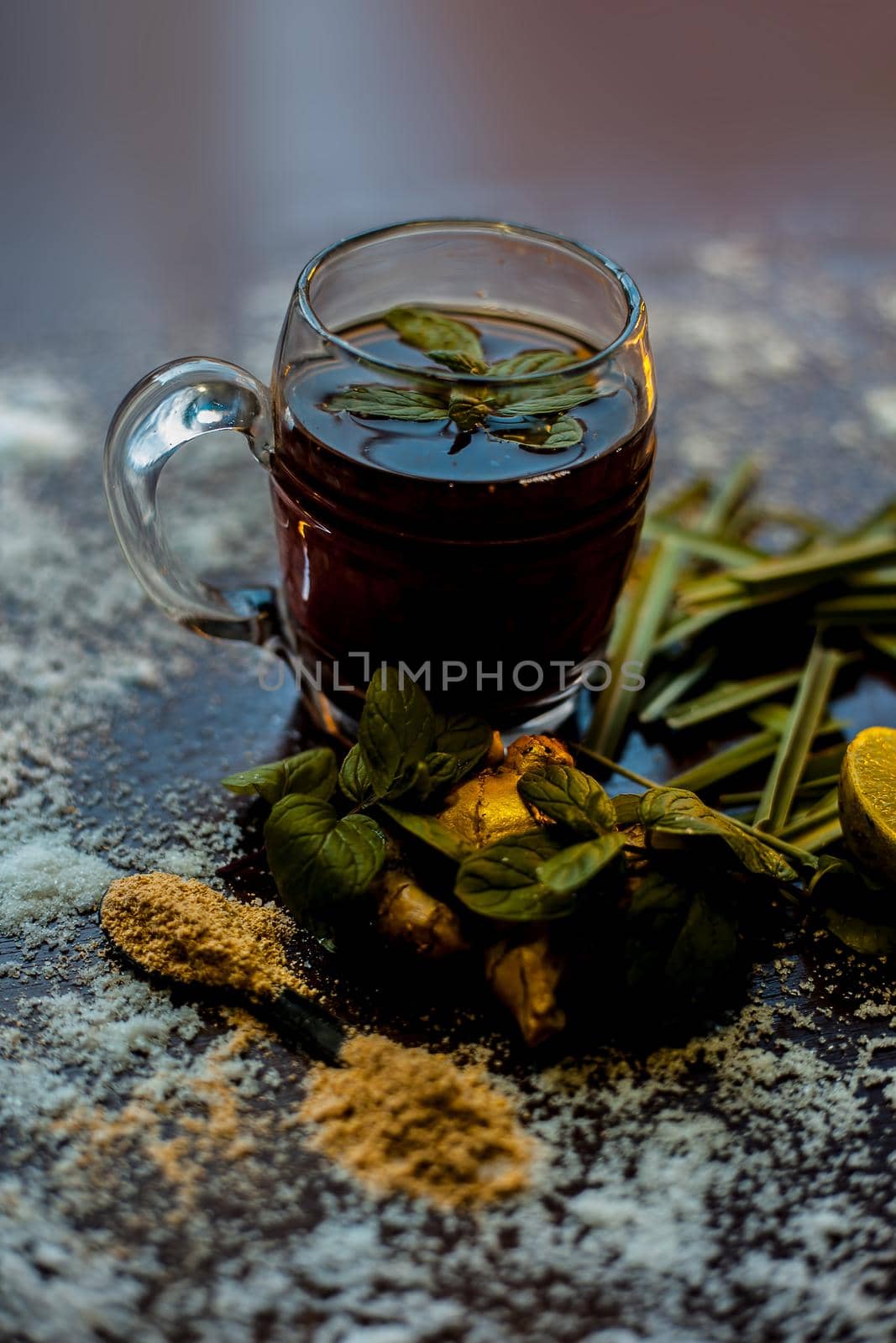 Shot of ayurvedic kada or immunity drink on brown surface consisting of lemongrass,lemon,mint leaves, soonth or dried ginger powder.