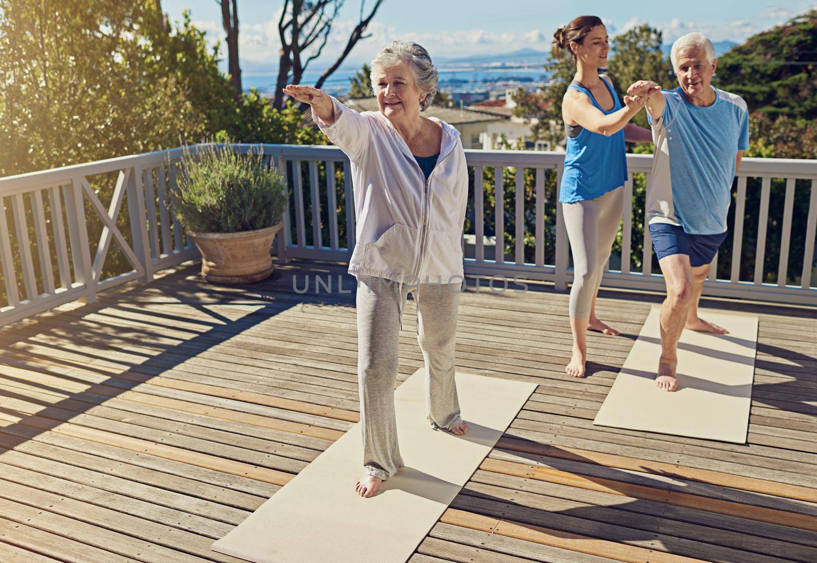 Yoga is exercise for the mind and body. a senior couple doing yoga together with an instructor on their patio outside