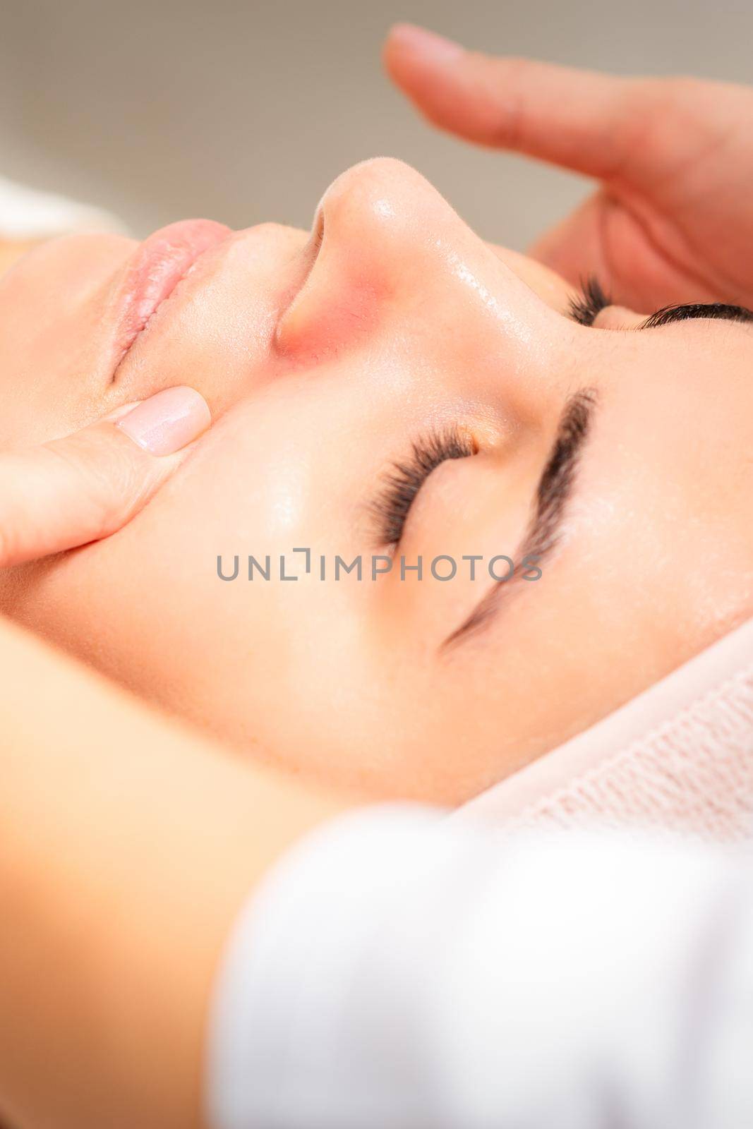 Beautician making lymphatic drainage face massage or facelifting massage at the beauty salon