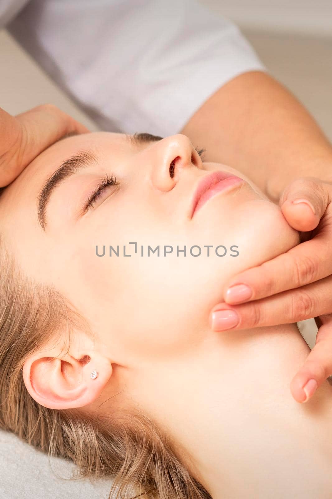 Young caucasian woman receiving a head and chin massage in a spa medical center