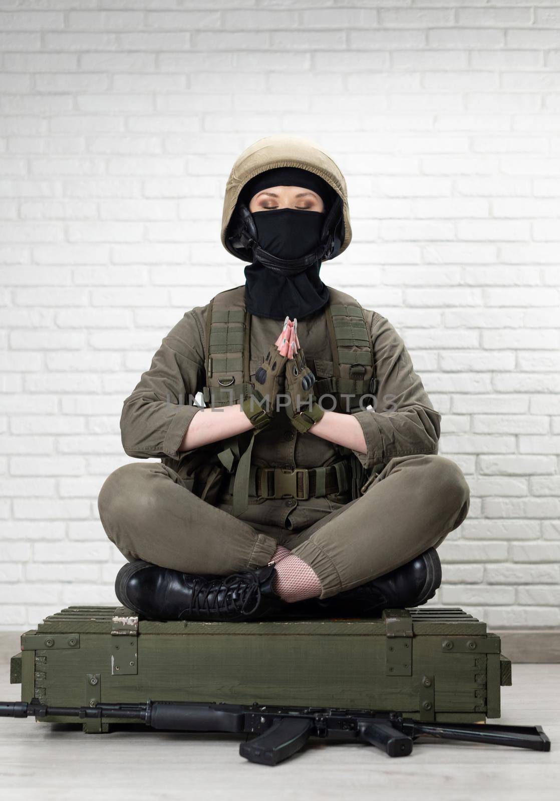 a girl soldier in a helmet sits in the lotus position on a box of ammunition by Rotozey