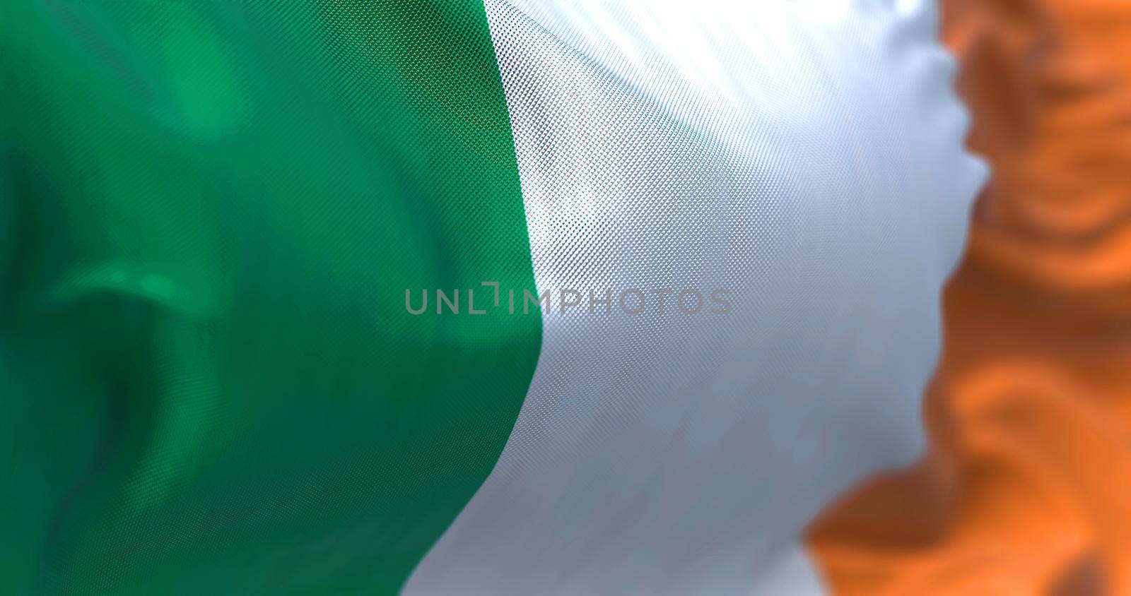 Close-up view of the irish national flag waving in the wind. Ireland is an island in the North Atlantic Ocean, in north-western Europe. Fabric textured background. Selective focus