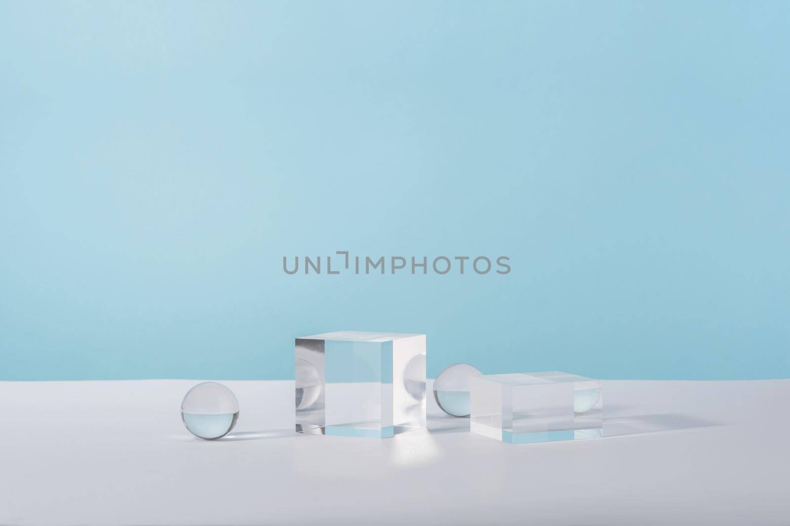 Pedestal cosmetic display glass podium platform with stylish props for product presentation, cosmetics geometric stand, mockup scene for jewellery mock up. Acrylic blocks and balls on blue background
