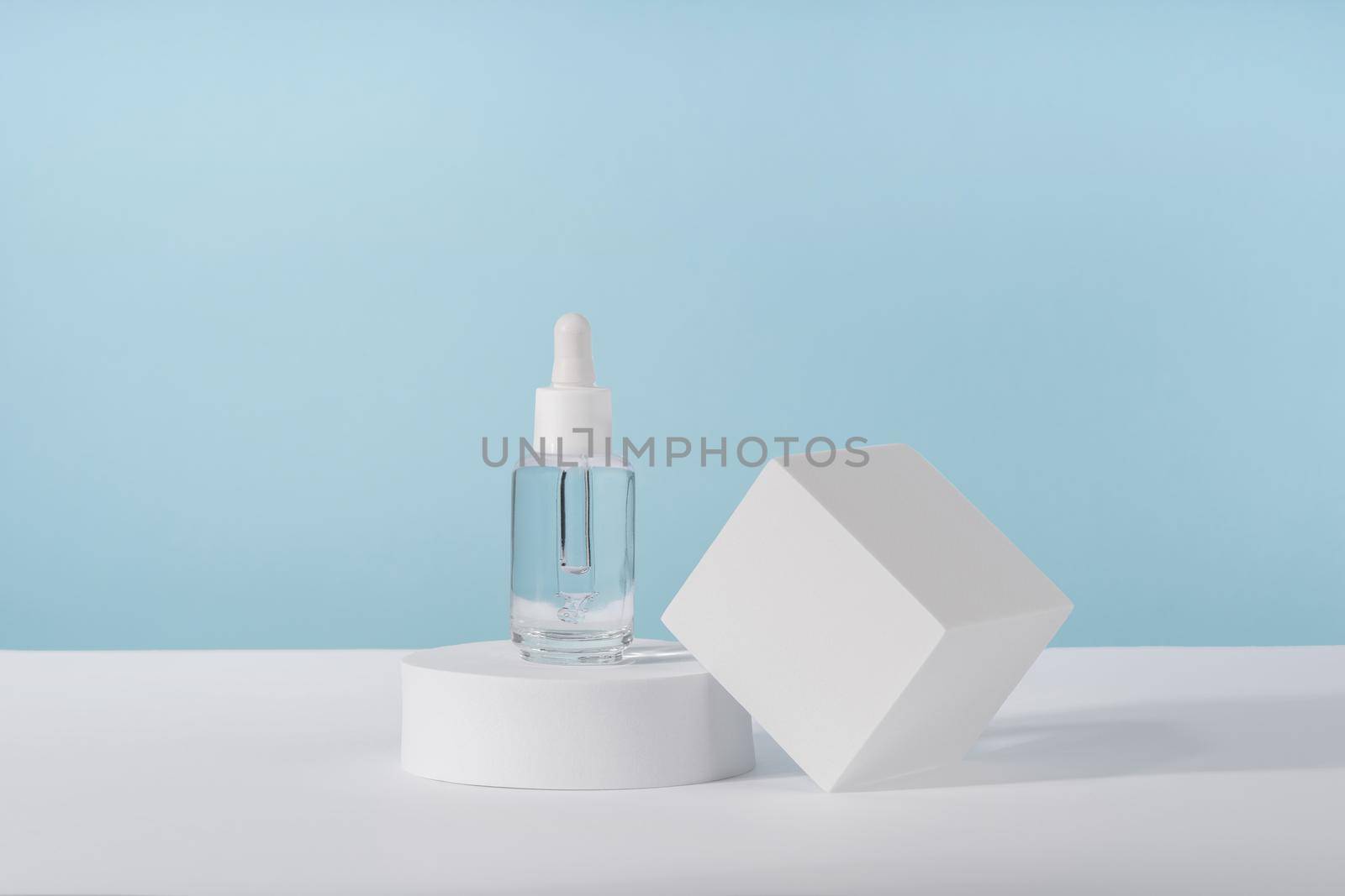 Serum cosmetic bottle with peptides and retinol on platform pedestal on blue background. Oil cosmetics transparent fashion product packaging with stylish props. Serum beauty dropper mockup by photolime