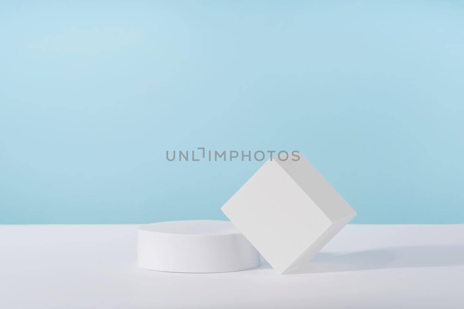 Podium pedestal for cosmetic product packaging on blue background. Showcase for jewellery presentation, white platform for perfume advertising, cosmetics stand background, branding scene by photolime