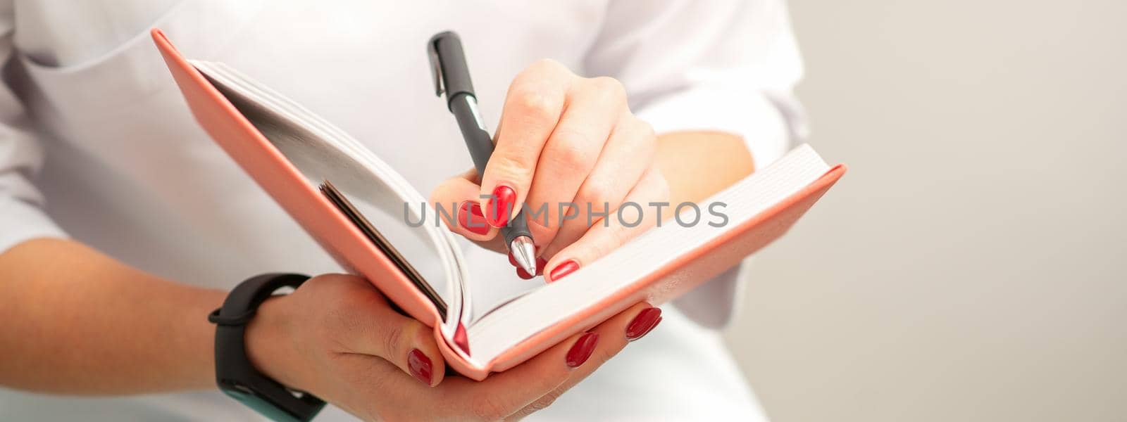 Close up of female doctor therapist writes notes in a medical notepad sitting in medical office