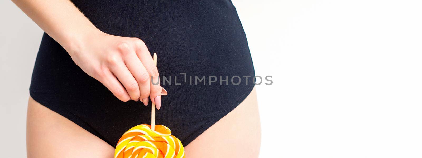 Woman holding lollipop candy on bikini zone, the concept of intimate depilation, problems of intimate hygiene