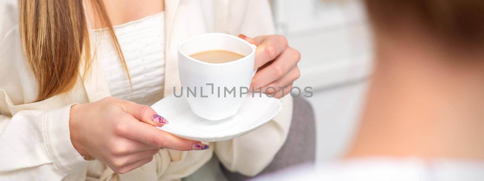 Young caucasian unrecognizable woman holding a cup of hot drink at a doctor's appointment in hospital office