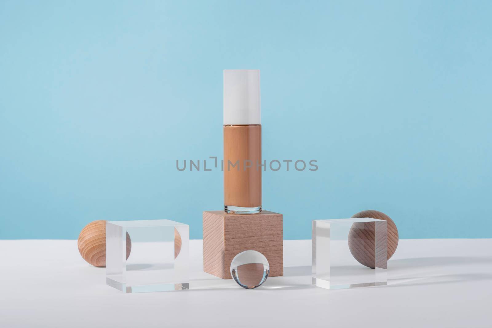 Cosmetic liquid foundation nude cream bottle mockup on acrylic and wooden block podium pedestal. Beige concealer base cosmetics product mock up on blue backdrop. Skincare beauty primer, corrector by photolime