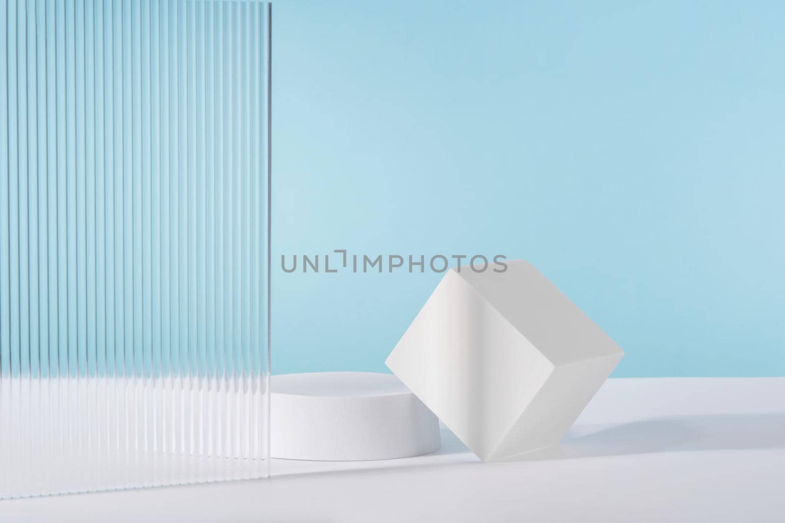 Acrylic plate, podium, background for cosmetic product packaging on blue backdrop with stylish props. Showcase for jewellery presentation, display for advertising, cosmetics branding scene by photolime