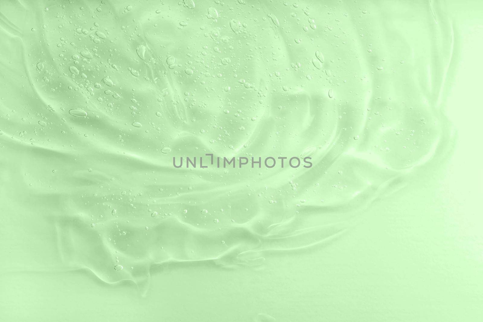 Aloe vera cosmetic gel texture with bubbles background. Skincare moisturizing product. Liquid green oil smudge. The concept of natural cosmetics. Hyaluronic acid clear serum sample. Close-up, macro.