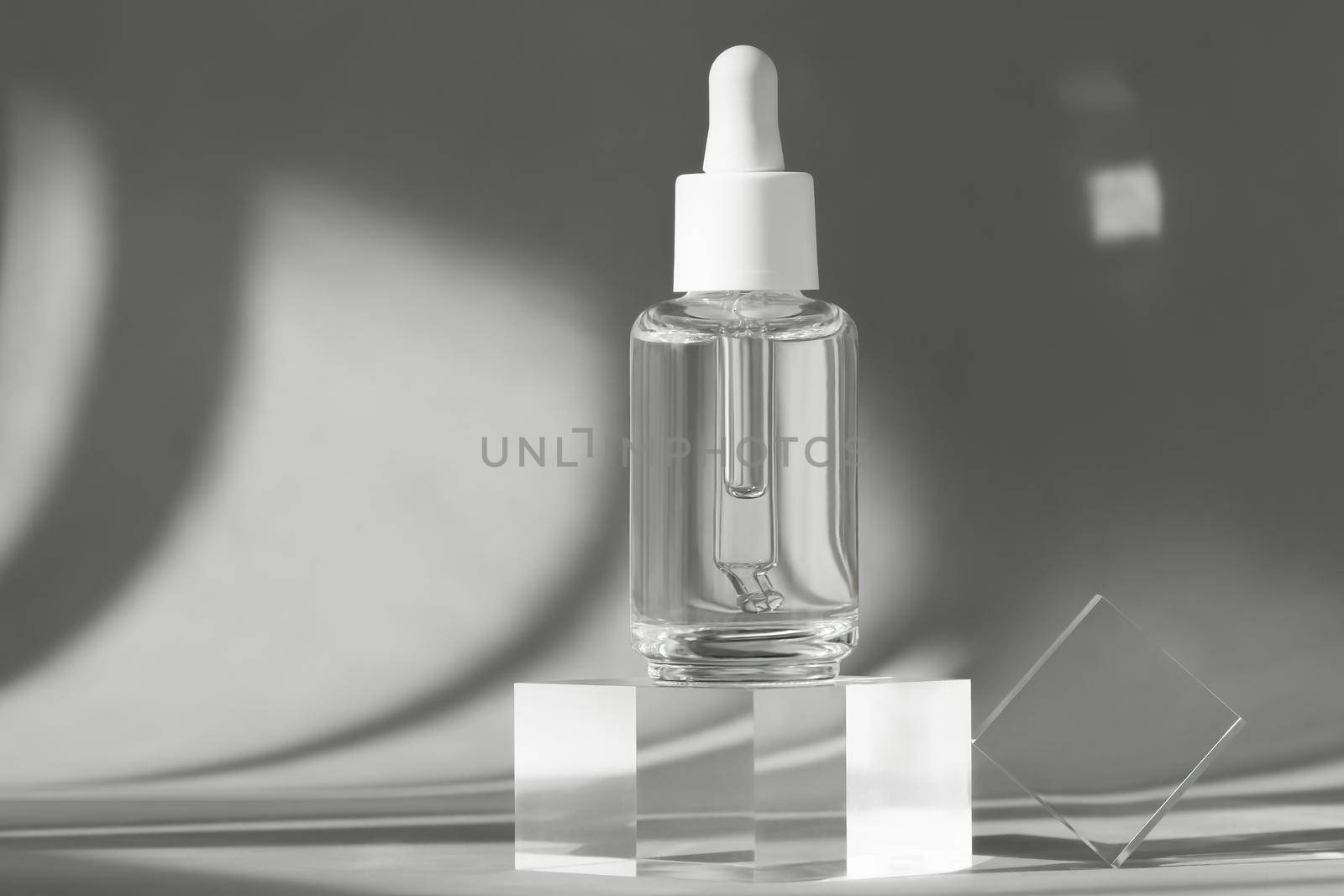 Serum bottle with peptides and retinol product packaging on modern acrylic transparent blocks with shadows from sun, cosmetic mockup on geometric stand, pedestal, cosmetics podium by photolime