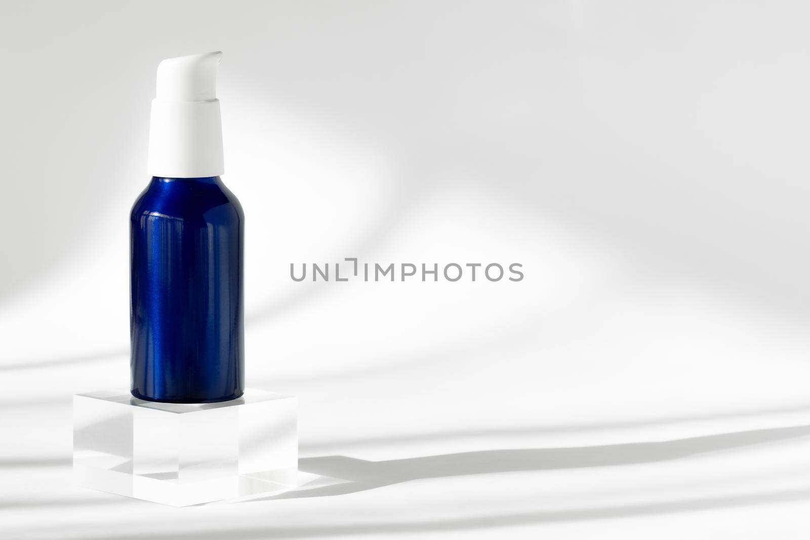 Blue cream cosmetic bottle on acrylic geometric pedestal podium block, product packaging with natural shadows from windows, creme lotion cosmetics podium presentation mockup. by photolime