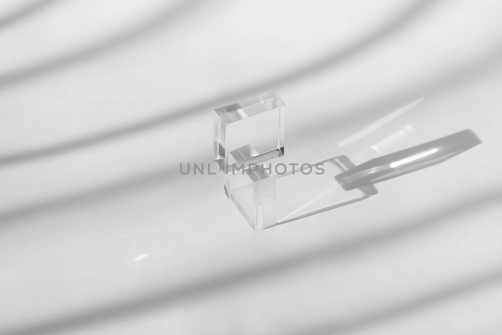 Pedestal cosmetics display glass blocks on surface, transparent geometric acrylic decor, mockup scene with sun shadow from windows in room. Abstract white background for cosmetic product presentation