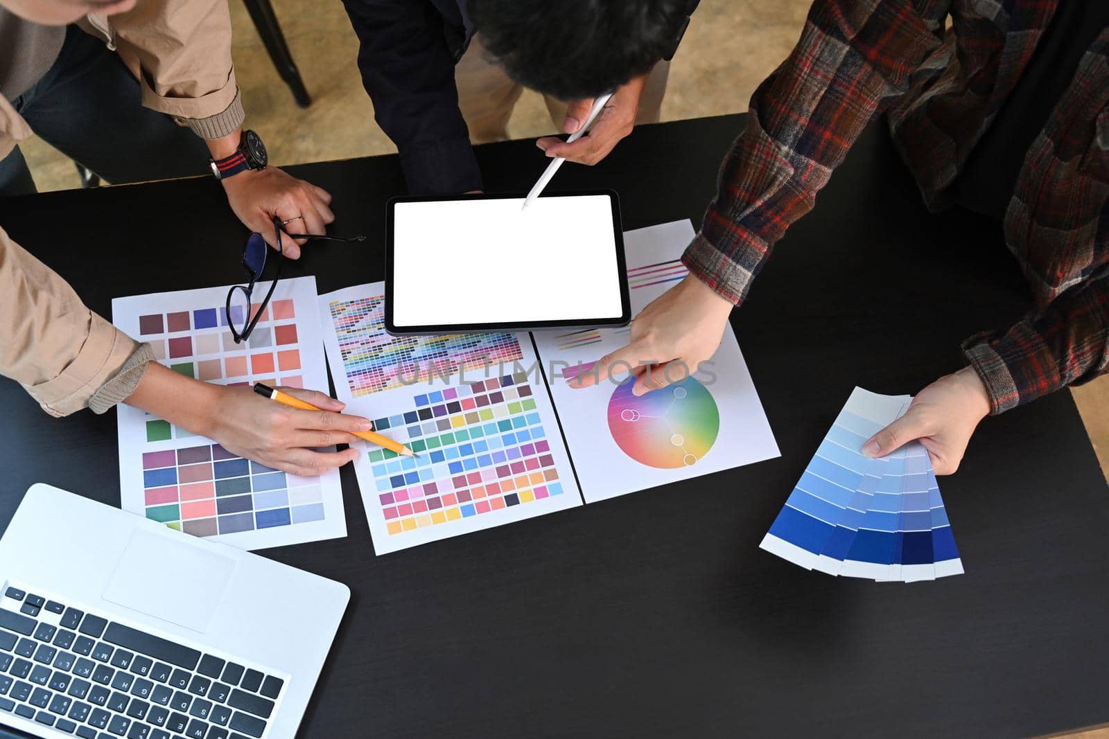 Overhead view group of young graphic designer working with color swatches together in in creative workplace.