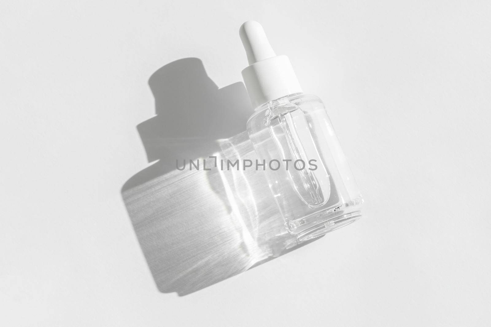 Transparent liquid product packaging in glass bottle. Anti aging serum with collagen and peptides on white with sunlight and shadow. Hyaluronic or polyglutamic acid oil cosmetic mockup. by photolime