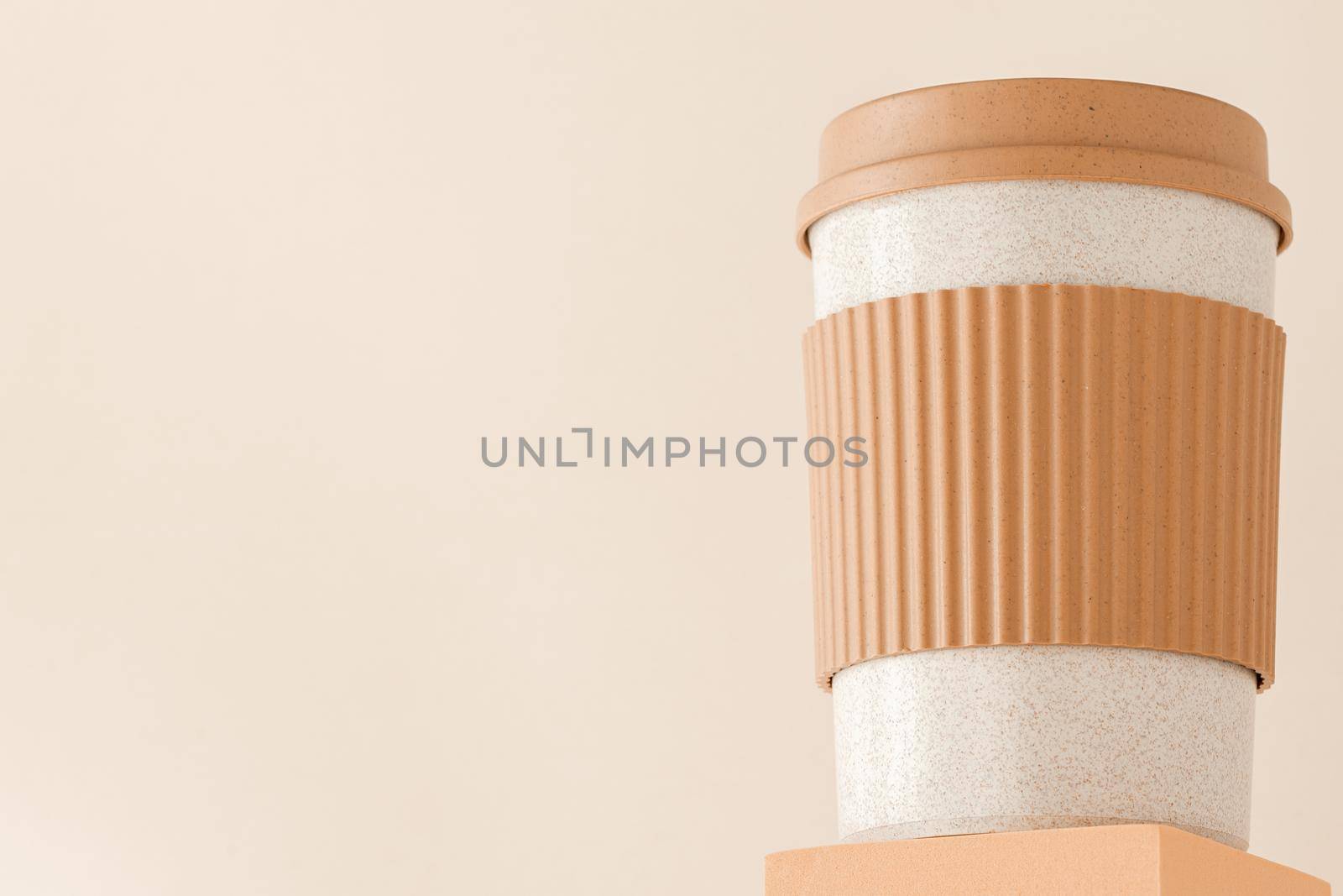 Reusable cup, biodegradable travel plastic coffee mug on platform showcase. Bamboo eco friendly cup on display pedestal. Zero waste, sustainability, sustainable lifestyle by photolime