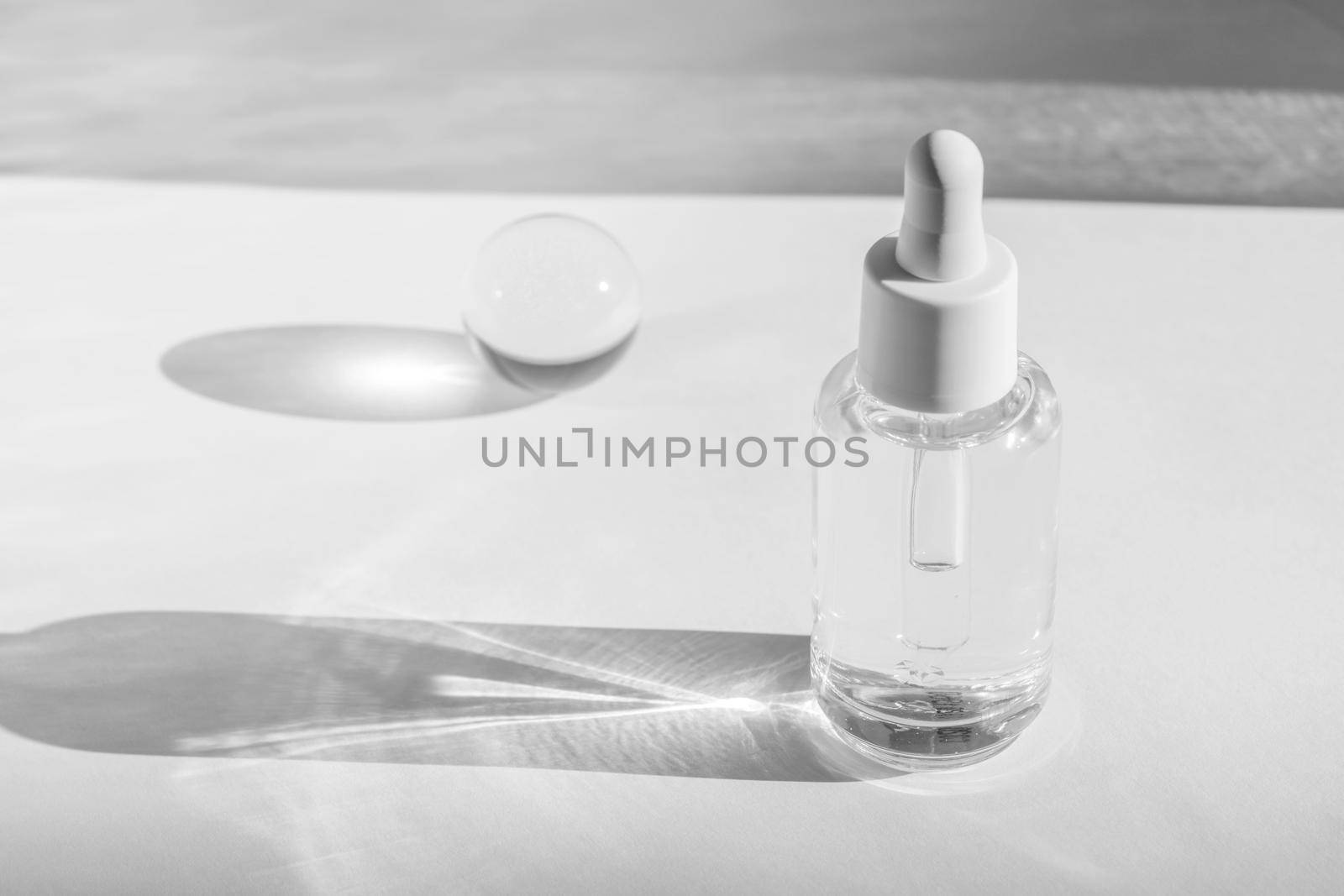 Hyaluronic or polyglutamic acid oil cosmetic mockup. Anti aging serum with collagen, retinol and peptides on white with sunlight and shadow decor. Liquid essence product packaging bottle. Copy space