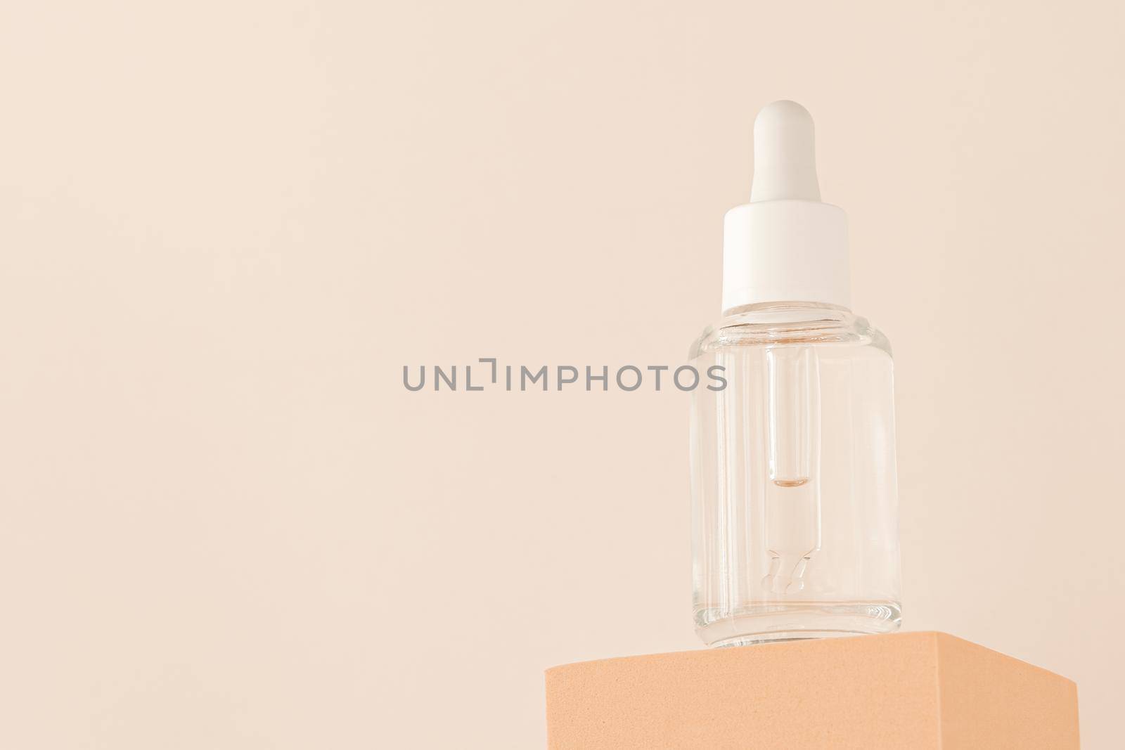 Hyaluronic acid, serum skincare glass bottle on beige podium pedestal, low angle view. Serum product cosmetic with peptide and collagen. Modern brand cosmetics packaging with shadow. by photolime