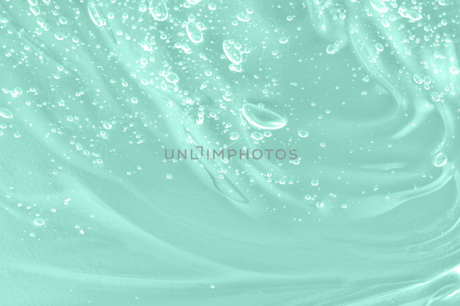 Skincare moisturizing product. Liquid green oil smudge. The concept of natural cosmetics. Hyaluronic acid clear serum sample. Aloe vera cosmetic gel texture with bubbles background. Close-up, macro.